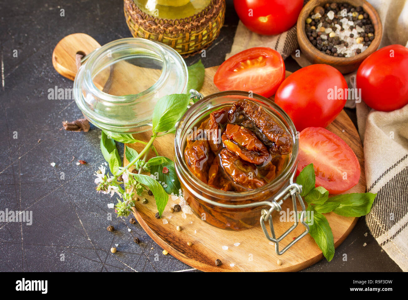 Sun dried tomatoes with olive oil in a jar on black stone or concrete