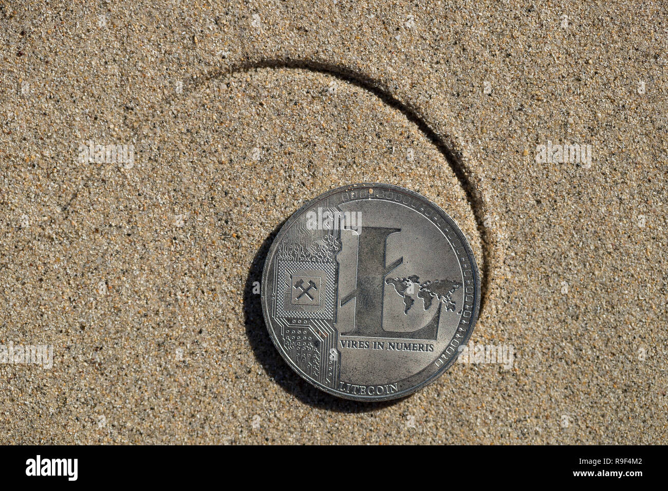 Litecoin cryptocurrency physical coin flipped on the backside placed on the  sandy beach shore with the drawn Fibonacci spiral pattern Stock Photo -  Alamy