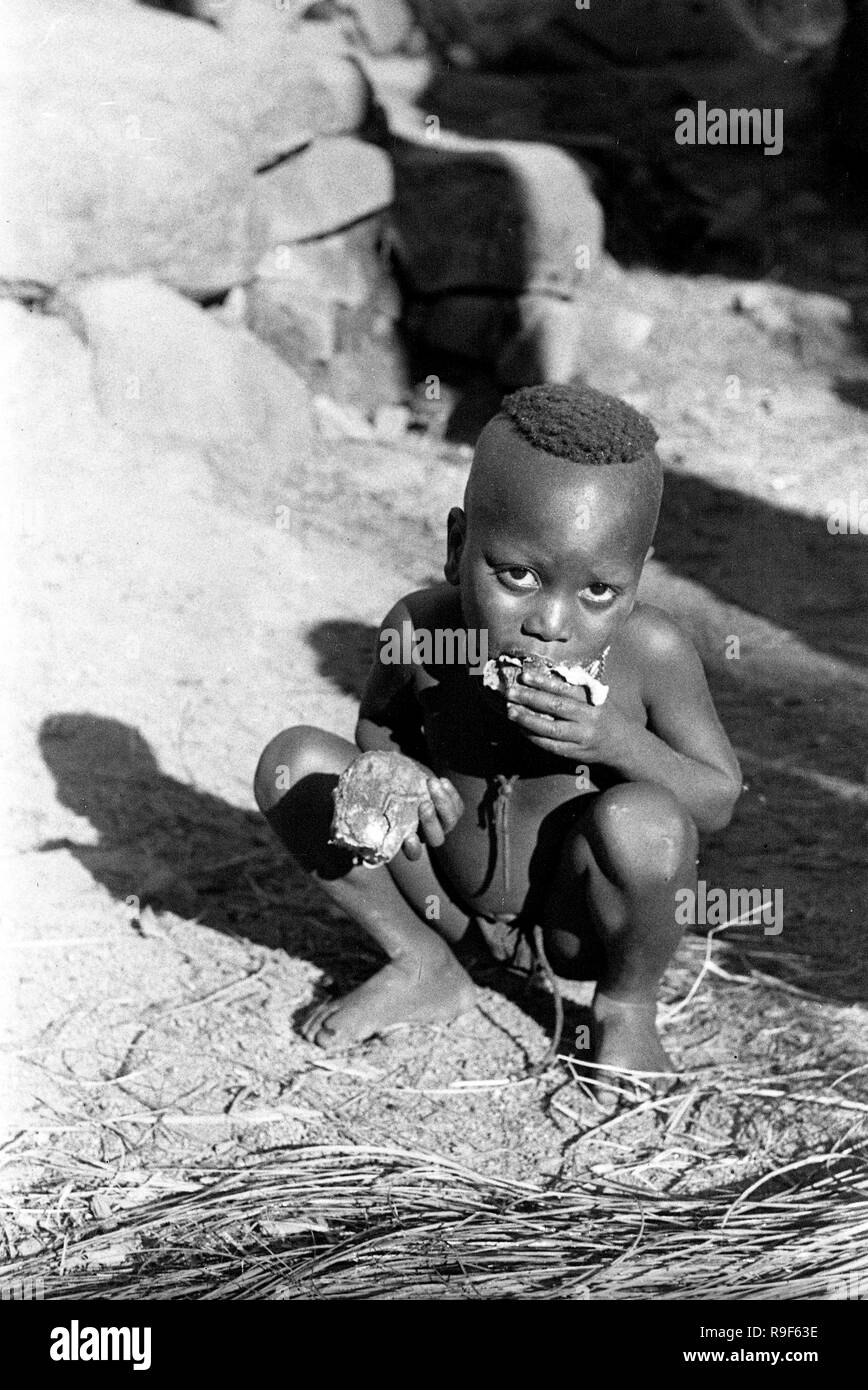 French West Africa 1958 hungry young boy eating Stock Photo