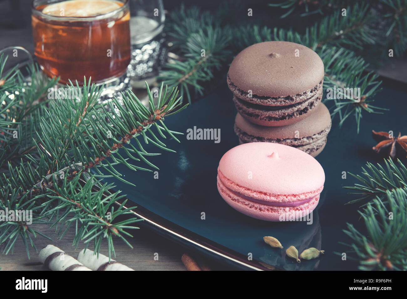 Fresh red macaroons at the Christmas table with the garland on the Christmas tree branches. Stock Photo