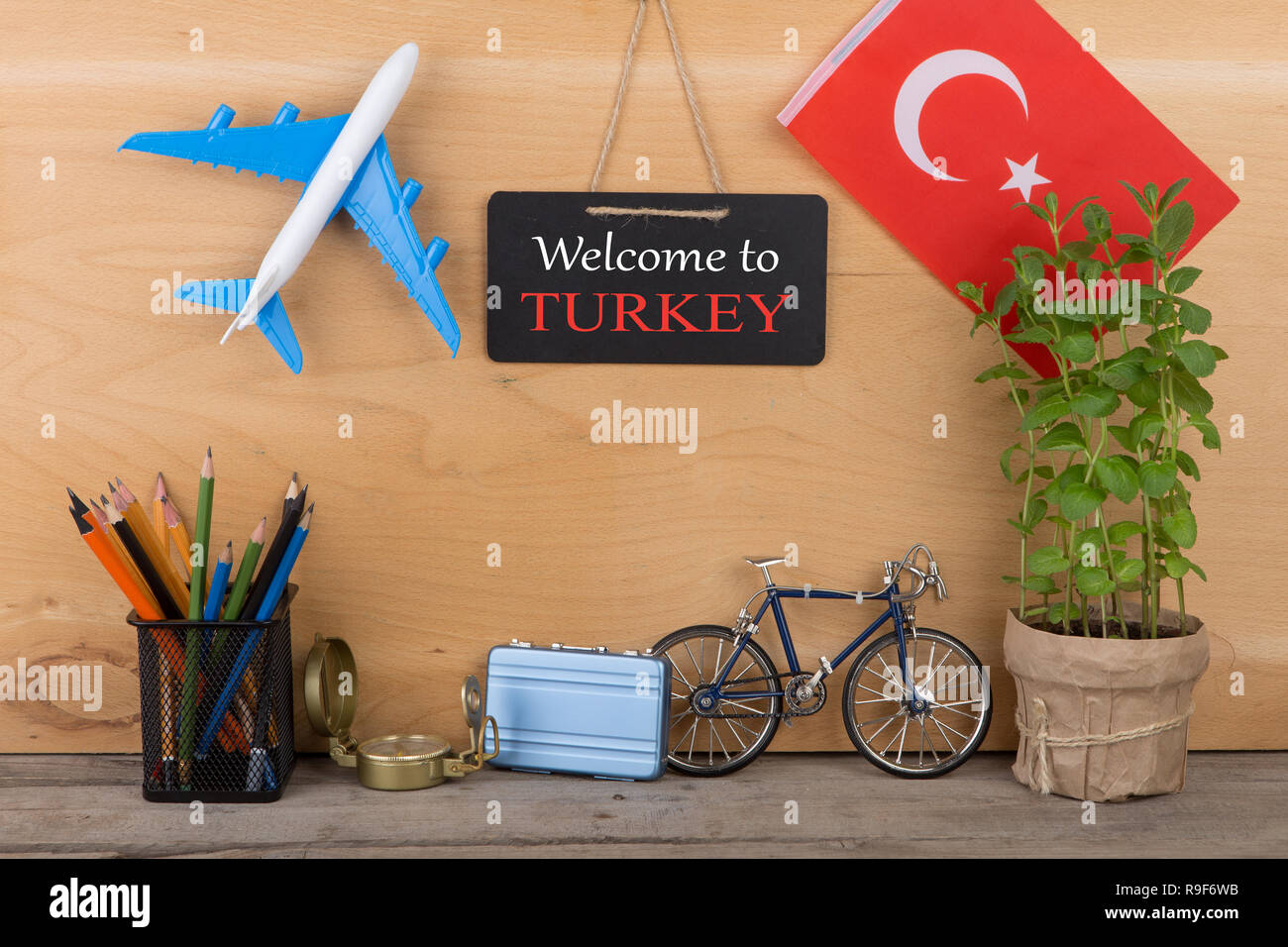 Travel time concept - blackboard with text 'Welcome to Turkey', flag of the Turkey, airplane model, little bicycle and suitcase, compass on wooden bac Stock Photo
