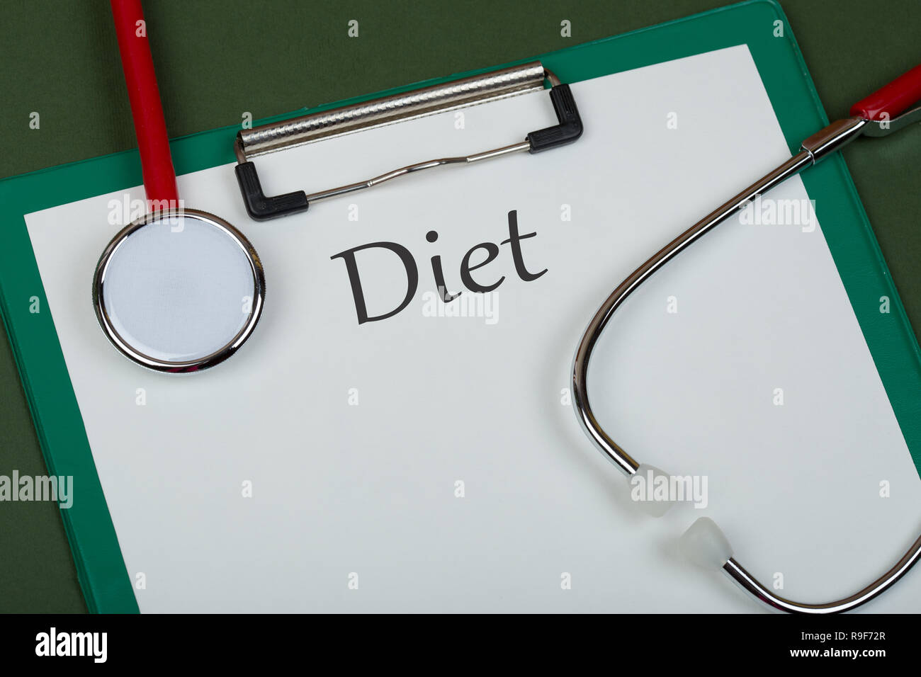 Doctor workplace - red stethoscope and clipboard with text 'Diet' on green paper background Stock Photo