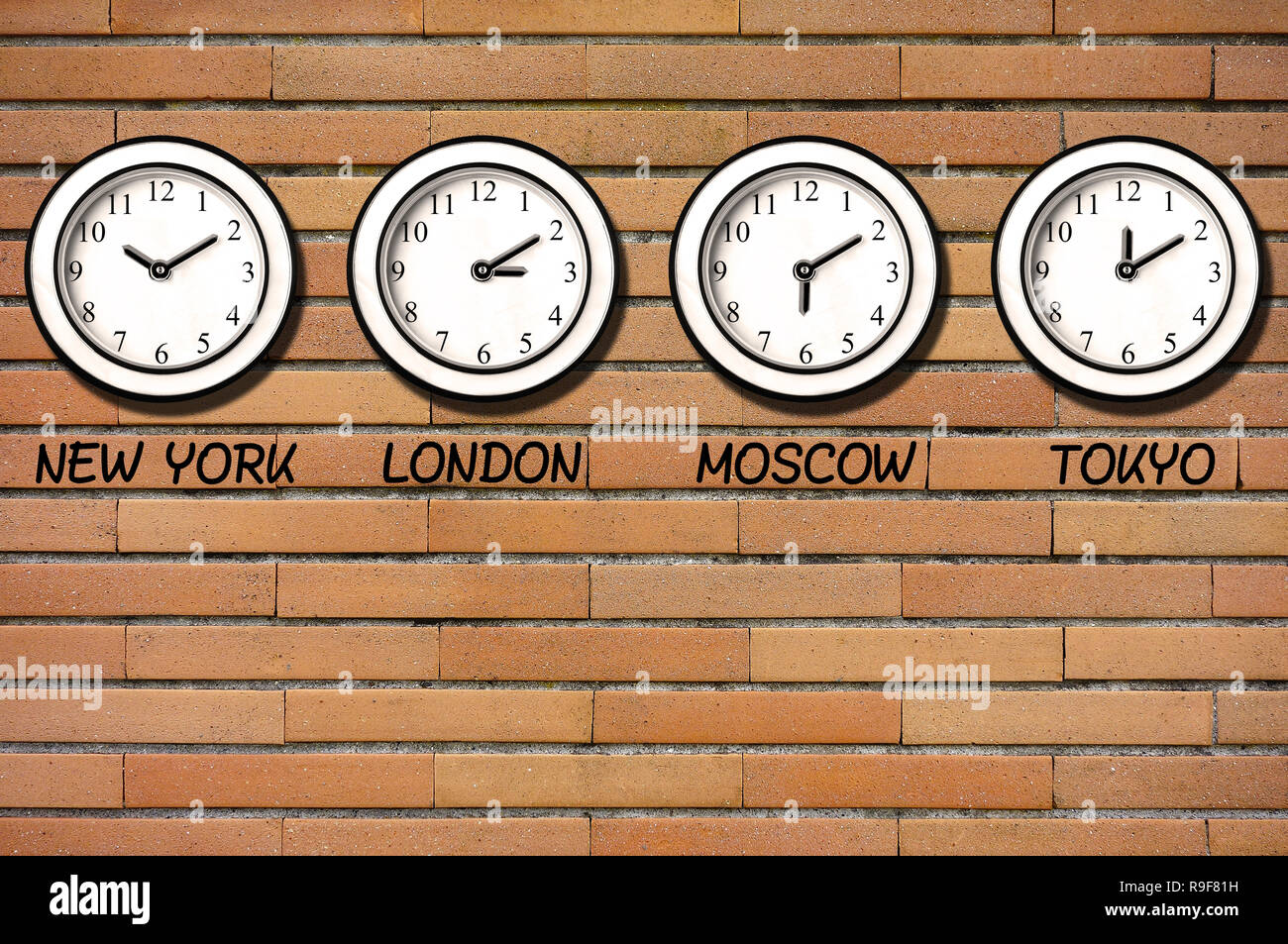 Classic wall clocks for different timezones on wall of bricks Stock