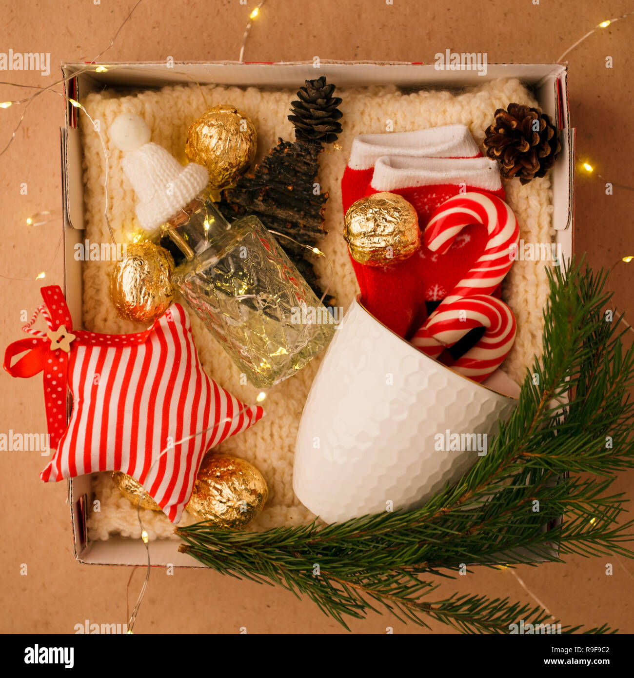 A personalized box with gifts for Christmas and New Year, a set of cute things, traditional sweets and decor, a simple idea for a nice gift for family Stock Photo