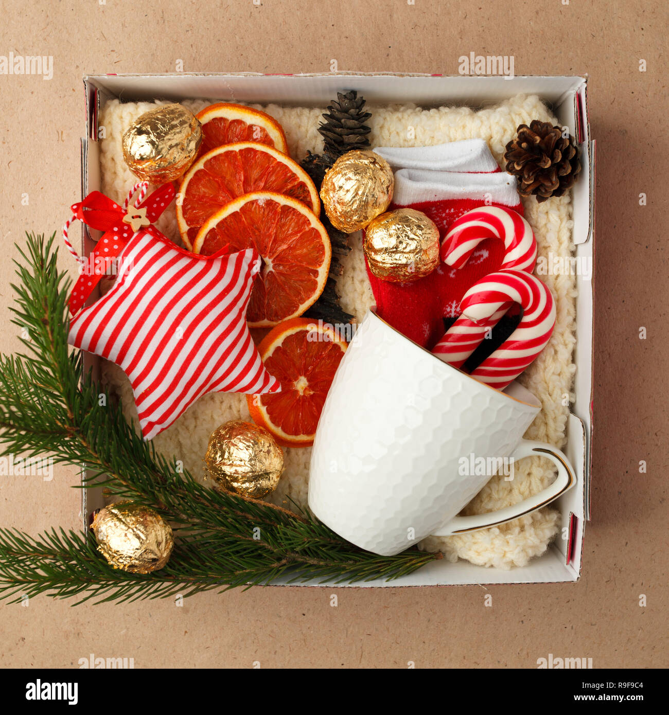A personalized box with gifts for Christmas and New Year, a set of cute things, traditional sweets and decor, a simple idea for a nice gift for family Stock Photo