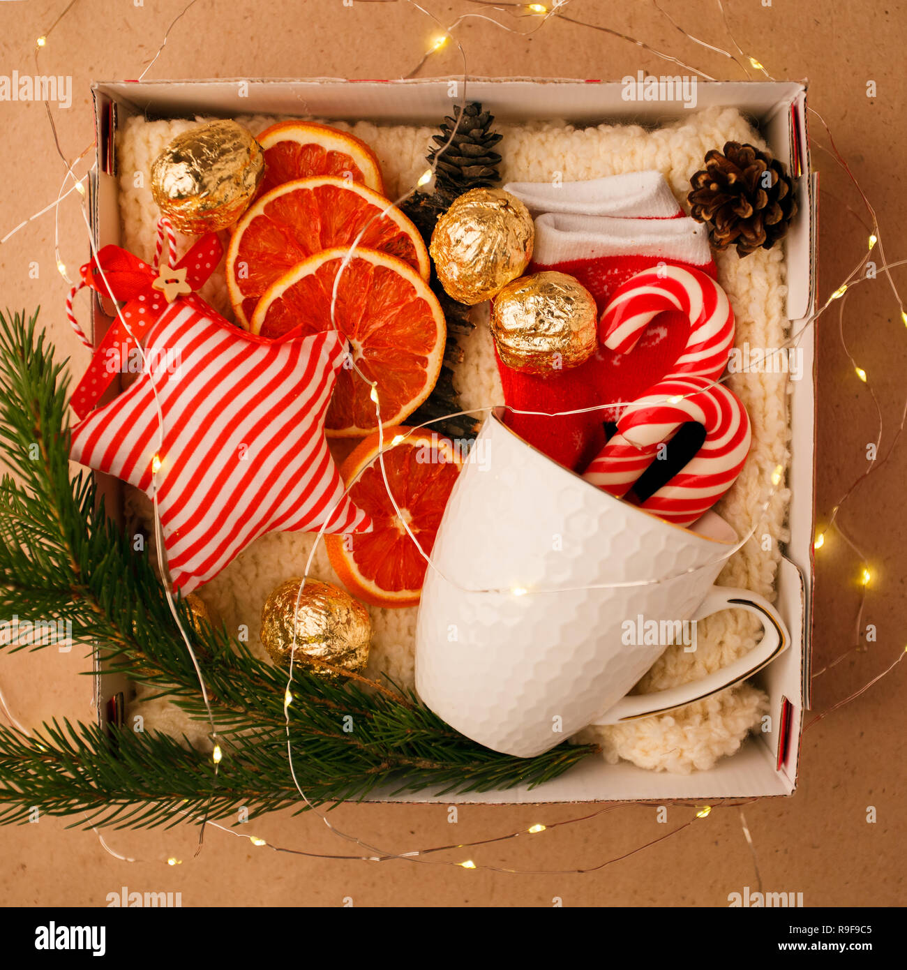 A personalized box with gifts for Christmas and New Year, a set of cute things, traditional sweets and decor, a simple idea for a nice gift for family Stock Photo