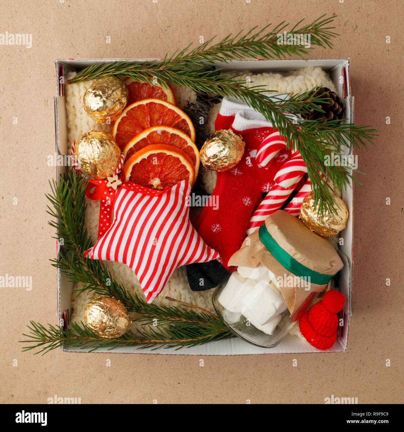A personalized box with gifts for Christmas and New Year, a set of cute things, traditional sweets and decor, a simple idea for a nice gift for family Stock Photo