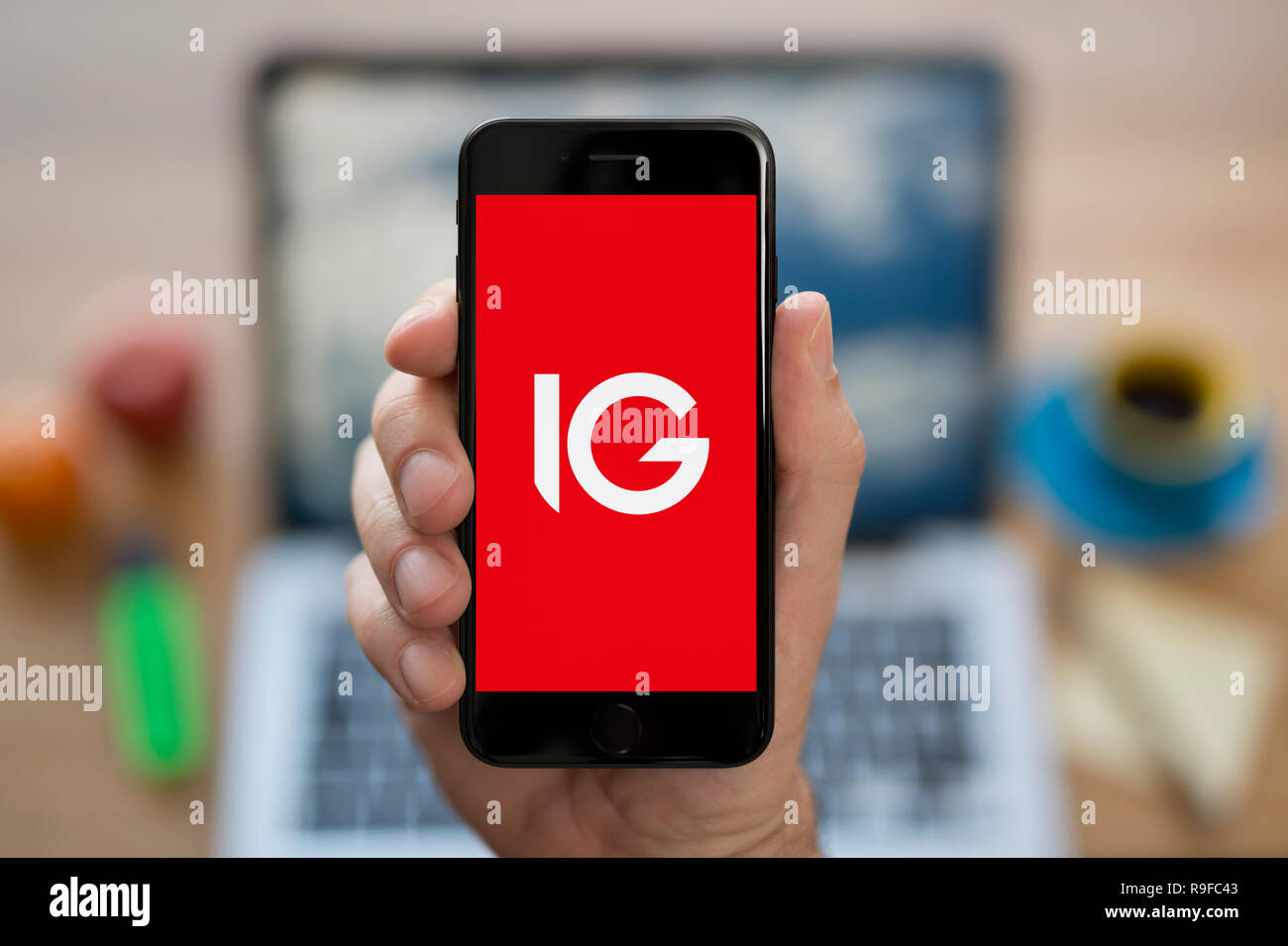 A man looks at his iPhone which displays the IG logo (Editorial use only). Stock Photo
