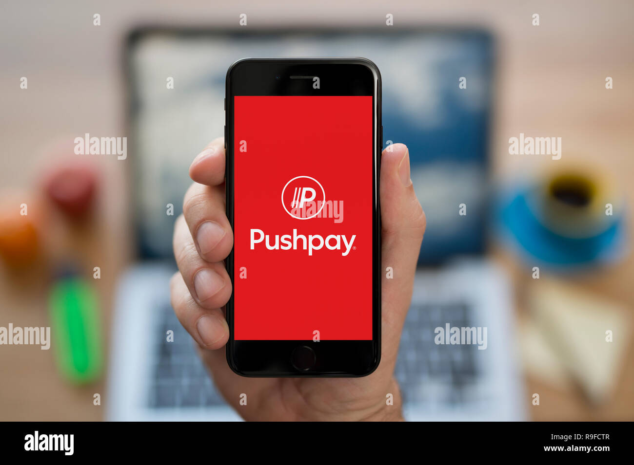 A Man Looks At His Iphone Which Displays The Pushpay Logo