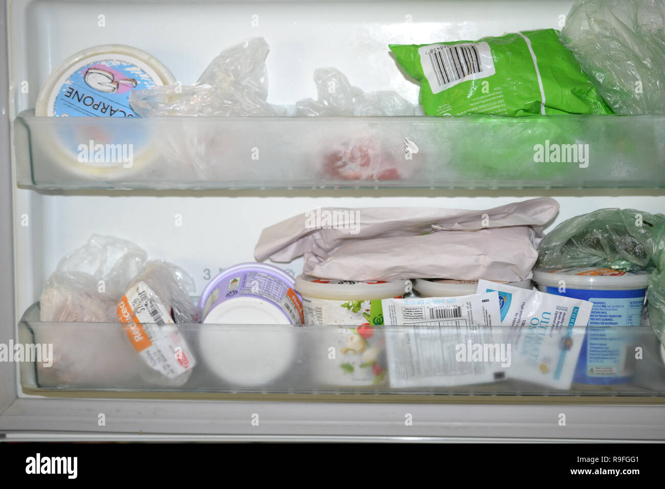 Freezer door compartments filled with food containers and wrapped food Stock Photo