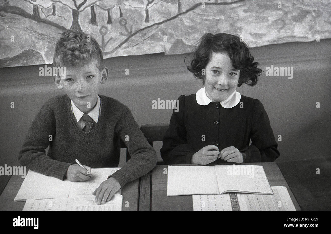 1950s, historical, primary school children, Langbourne School, England, UK. Picture shows a young boy and girl sitting next to each other at a two-seater wooden school desk with their class work. Stock Photo