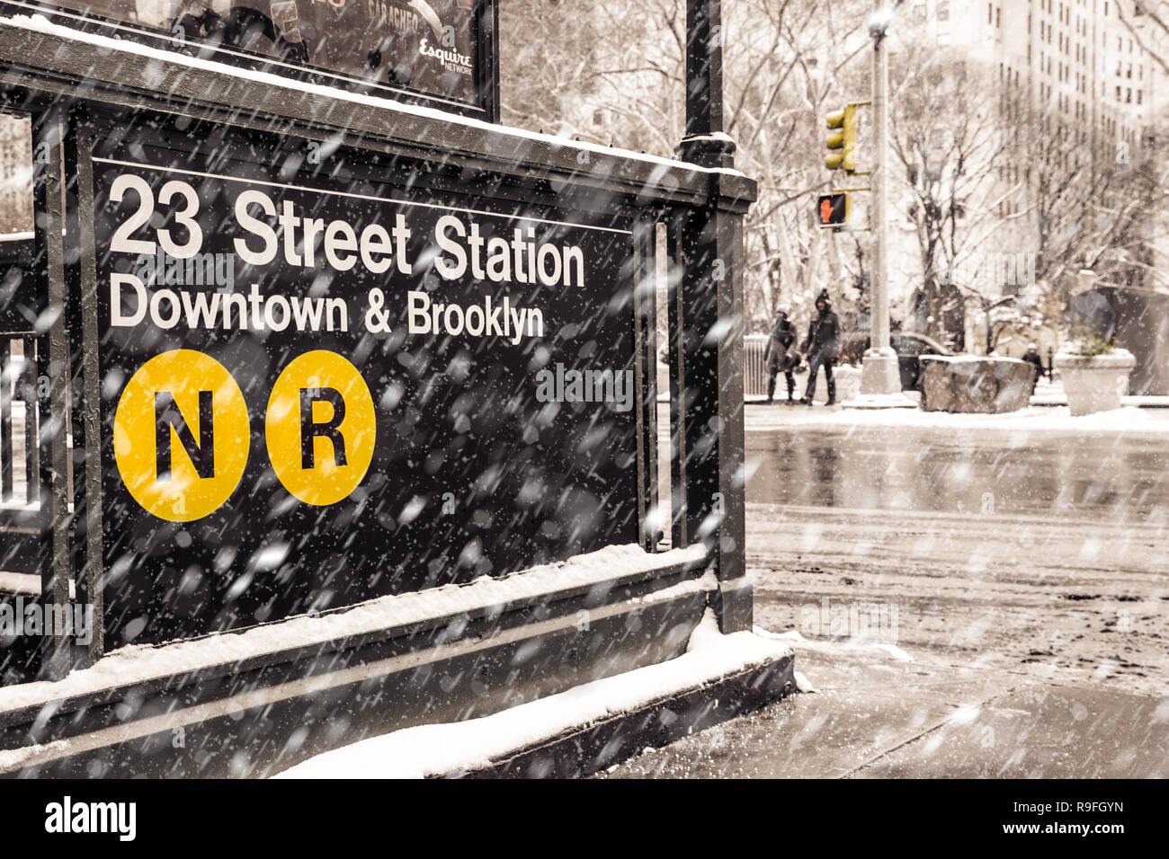 Midtown New York City Manhattan street scene at the 23rd subway street station with snowflakes falling during winter snow storm Stock Photo