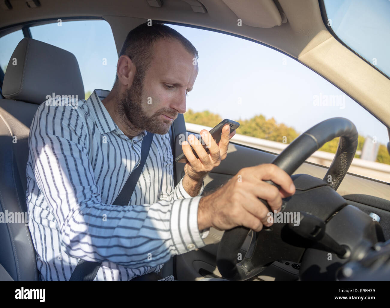 Dangerous man driving with his mobile phone Stock Photo - Alamy