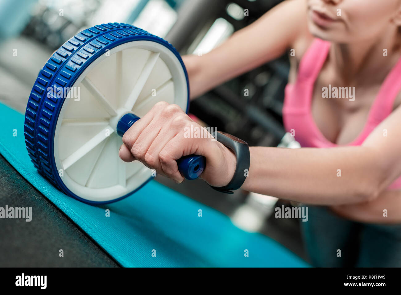 Young woman in gym healthy lifestyle on yoga mat rolling ab wheel wrist ...