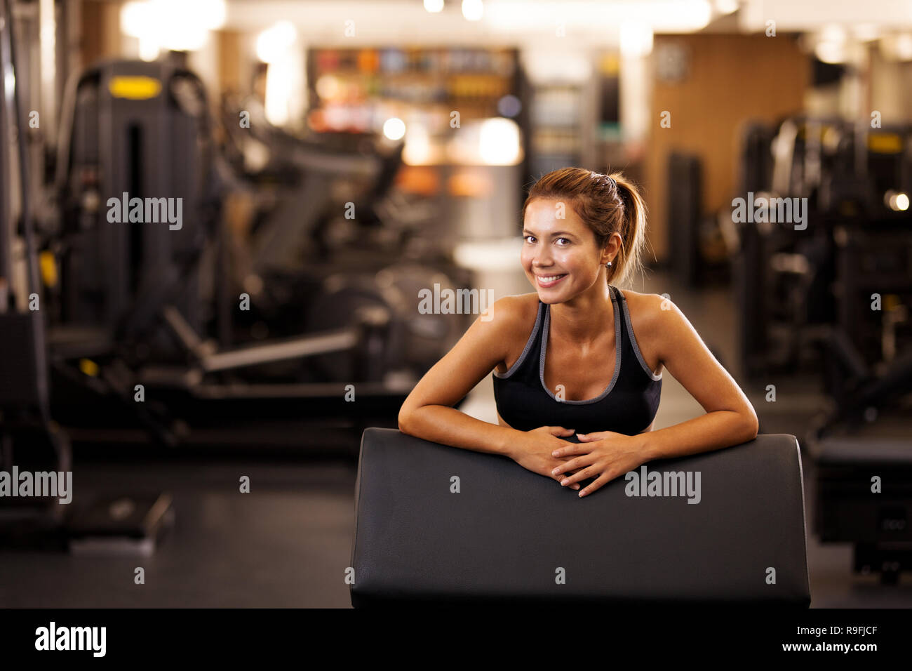 happy girl posing on a weight lifting seat in a generic out of focus