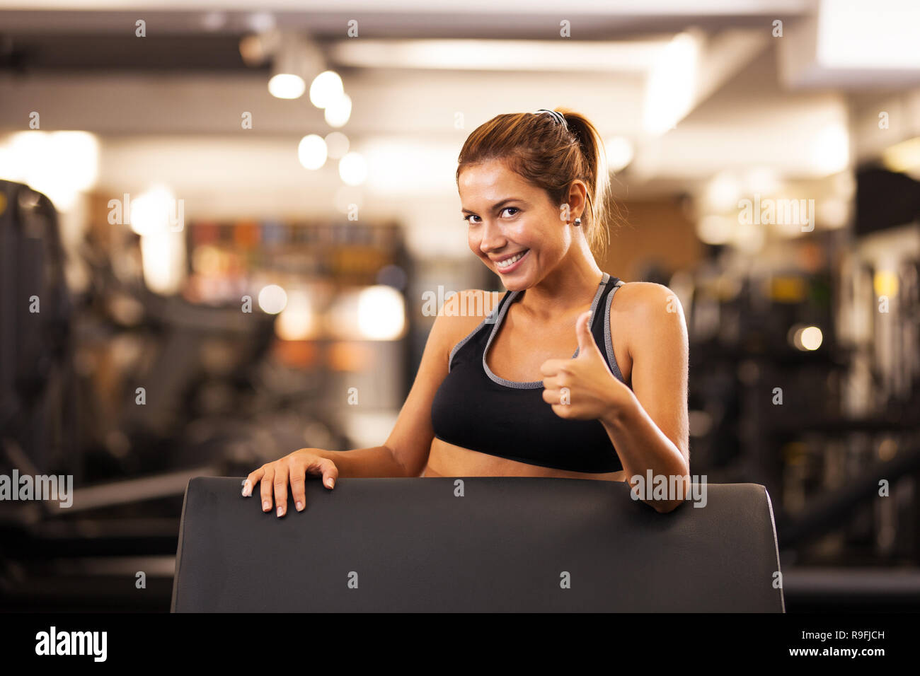 happy girl posing on a weight lifting seat in a generic out of focus