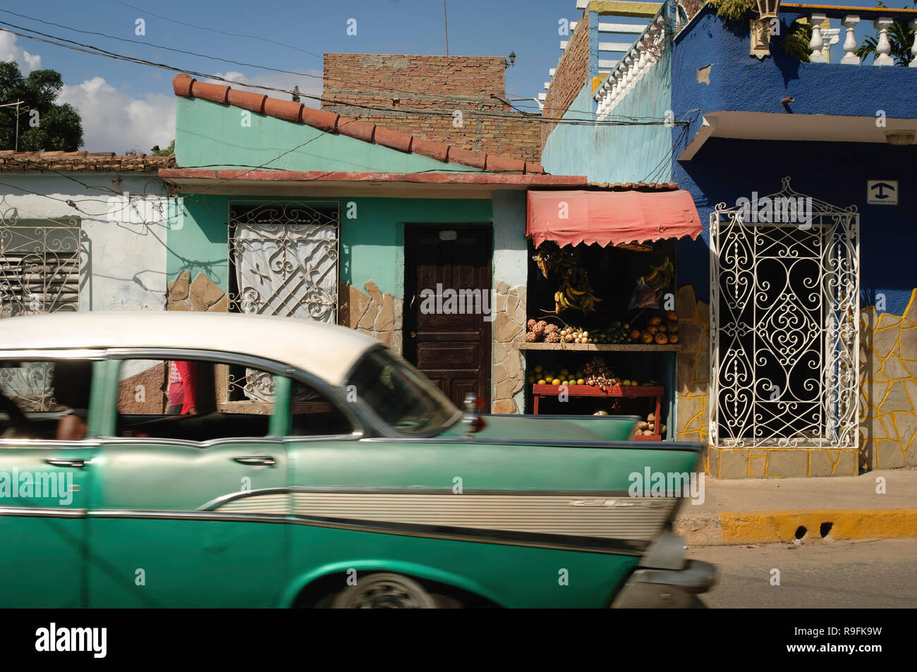A classic American green car in front of a typical fruit store on the streets of Trinidad, Cuba. Stock Photo