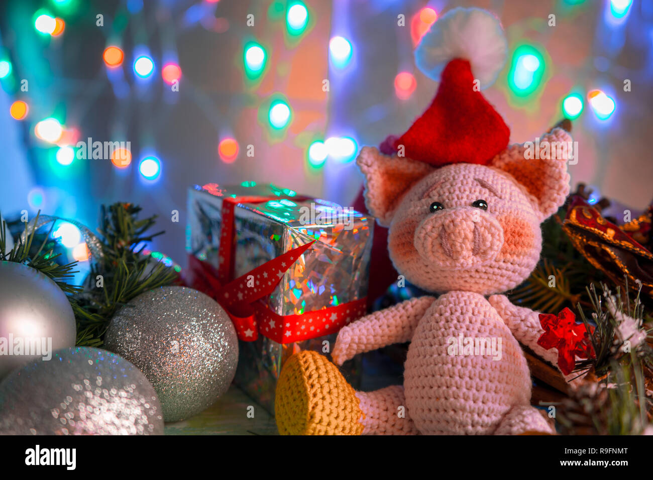 Funny greeting card with new year 2019. Pink pig with xmas balls and gift on background with illumination. Stock Photo