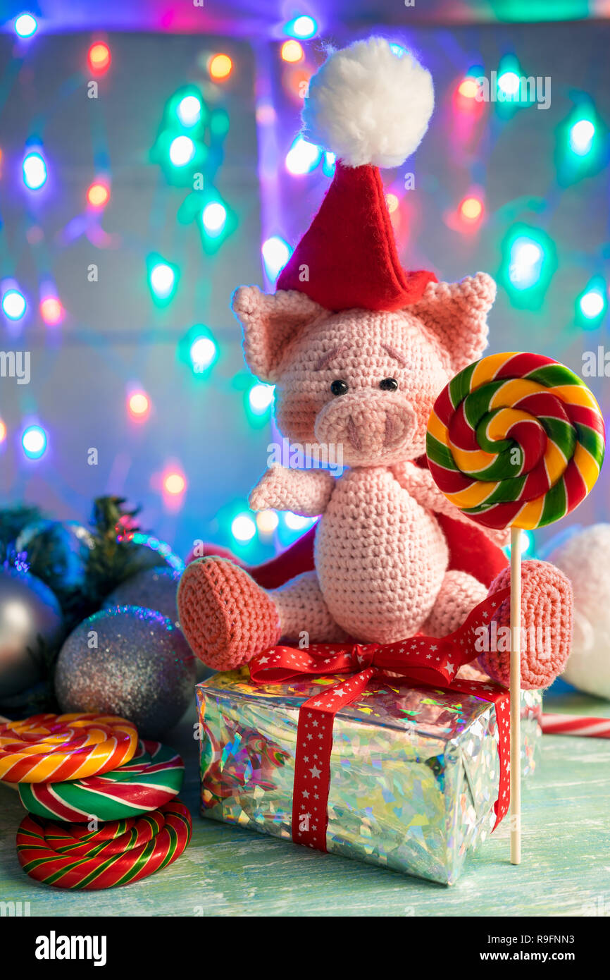 symbol 2019 pink pig sitting on a gift with lollipop on background with illumination. Stock Photo