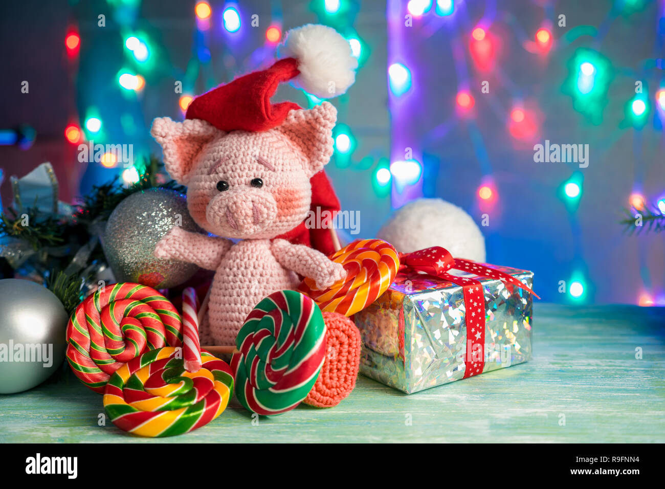 Funny greeting card with new year 2019. Pink pig with lollipops on background with illumination. Stock Photo