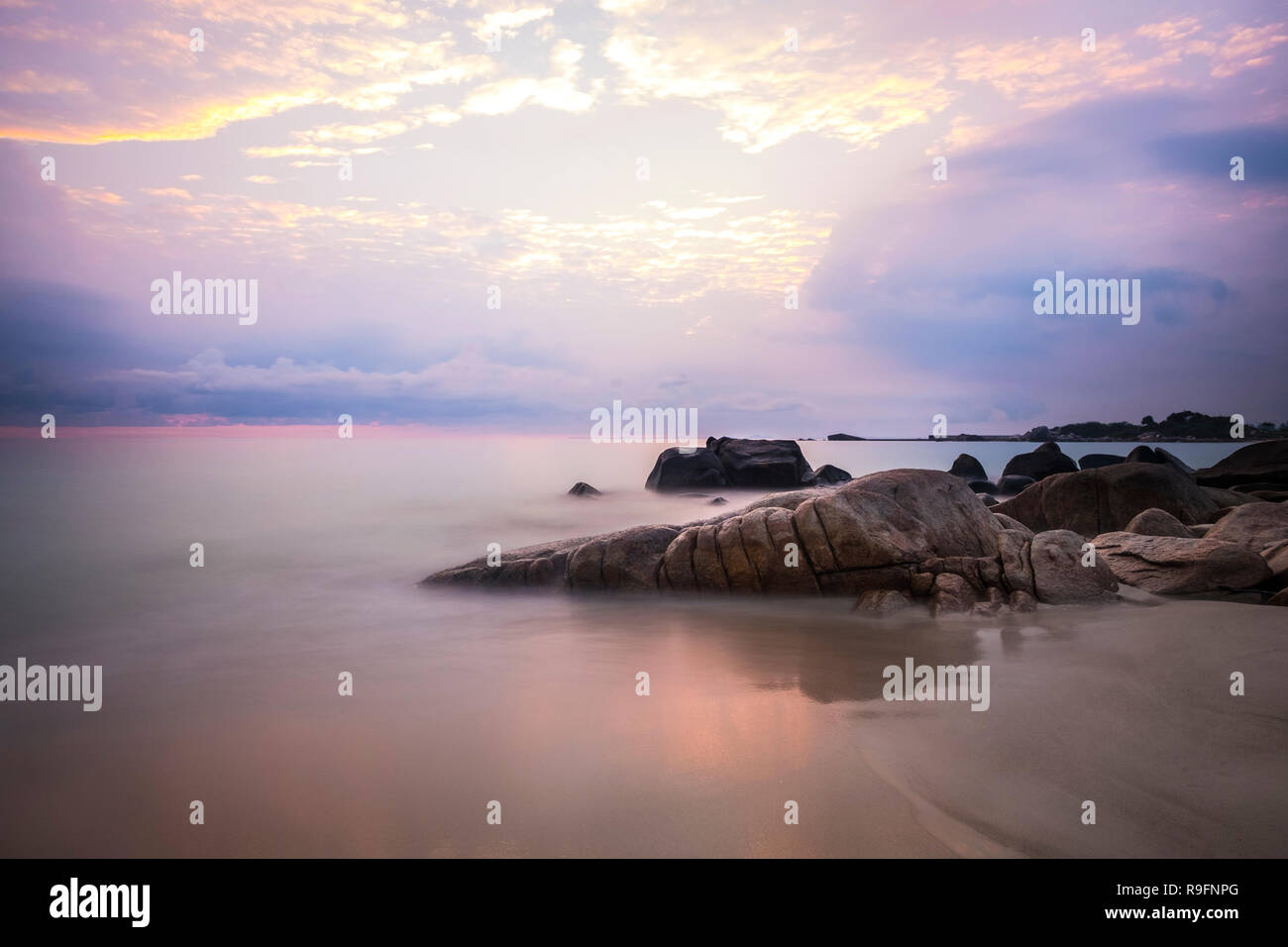 Sunrise at Bintan Island. Sand sea sky clouds and stones Stock Photo
