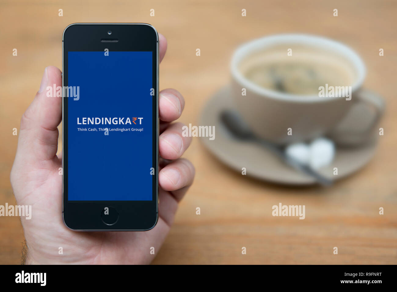 A man looks at his iPhone which displays the Lendingkart logo (Editorial use only). Stock Photo