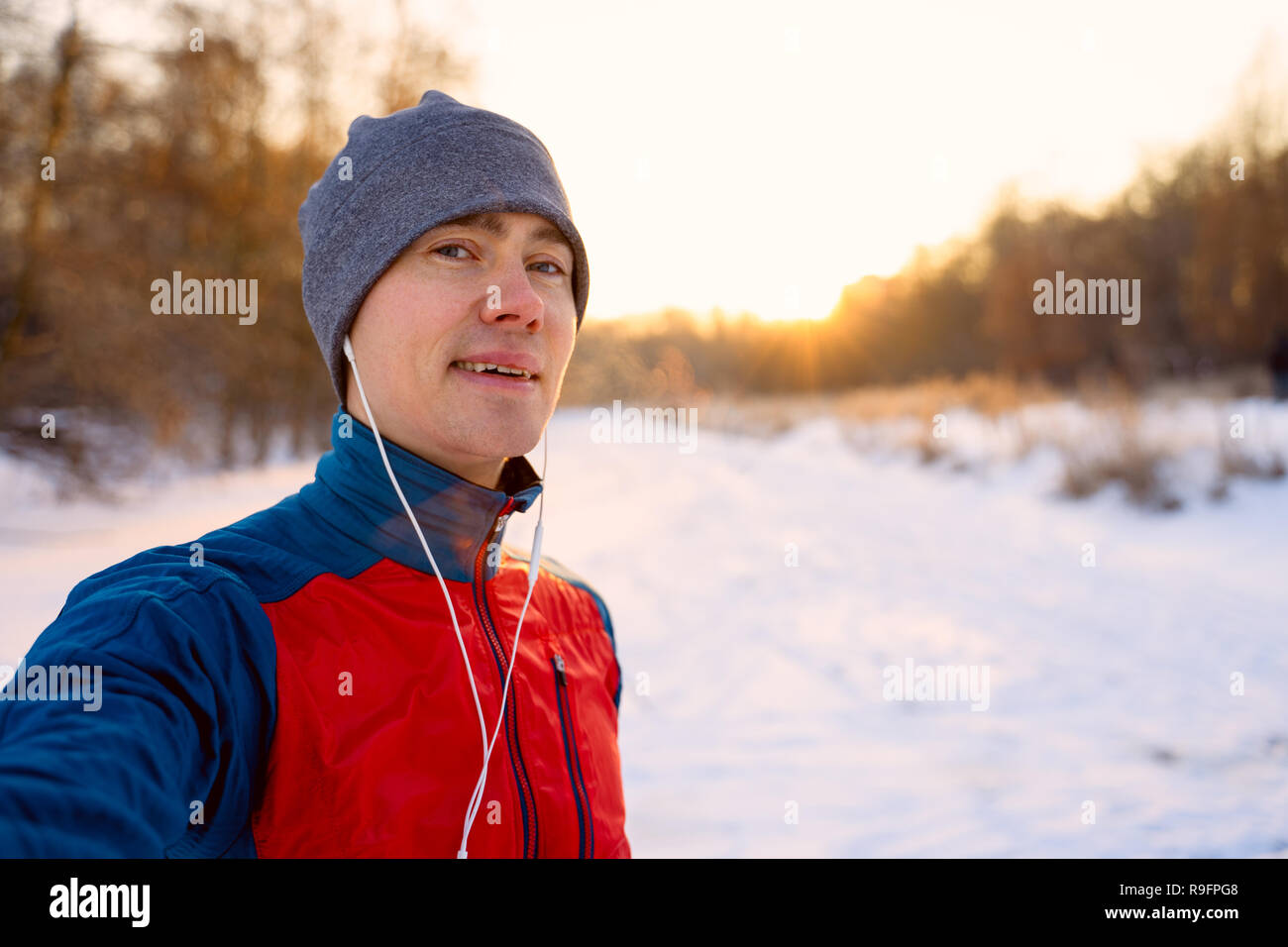 Runner wearing warm sporty clothes in headphones take selfie Stock Photo