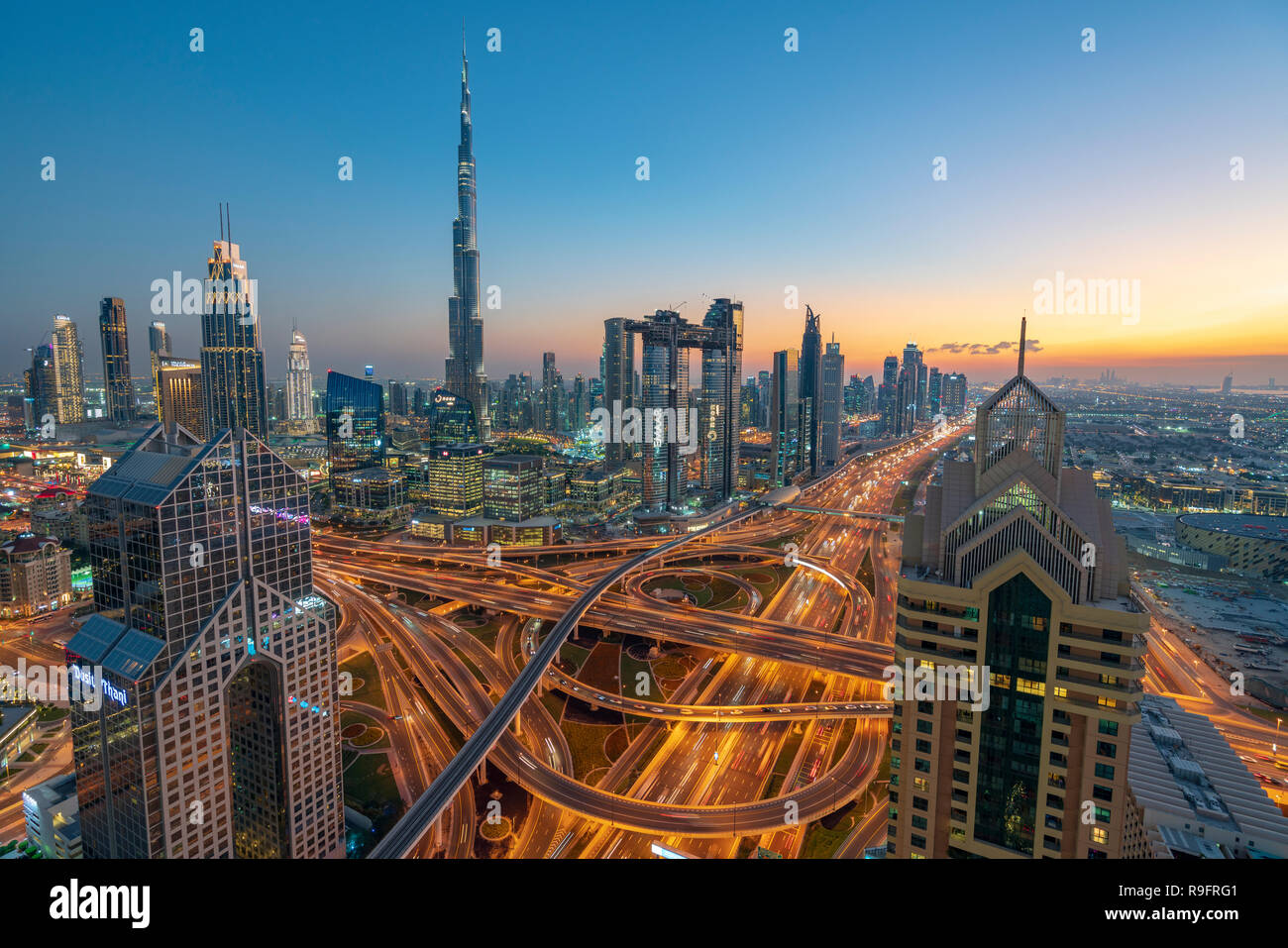 Cityscape view of Burj Khalifa and complex highway interchange and skyscrapers along Sheikh Zayed road in the evening in Dubai, United Arab Emirates,  Stock Photo