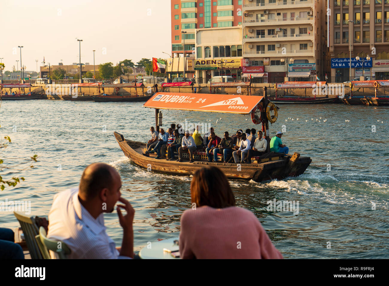 People in cafe beside The Creek at sunset in Old Dubai, United Arab Emirates. Stock Photo