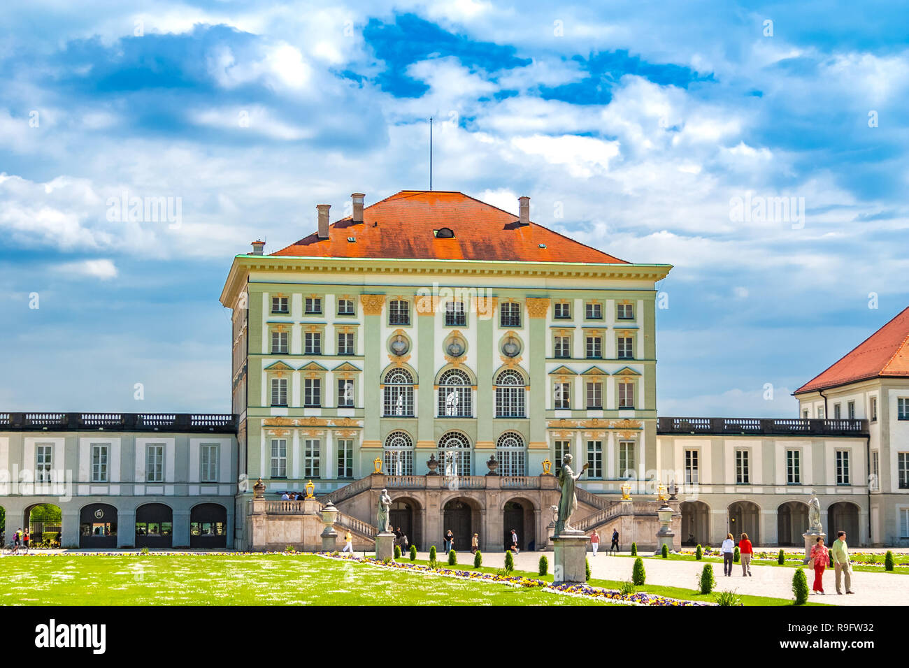 Great back view of the central pavilion of Munich's famous Nymphenburg Palace. Visitors enjoy a stroll in the Grand Parterre of the baroque palace. Stock Photo
