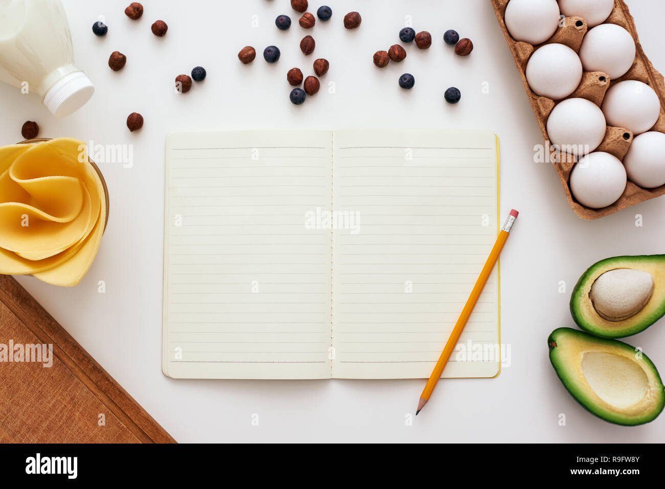Ready to write a recipe. Pencil and cookbook are lying on the table near dryed berries, honey, avocado and eggs Stock Photo