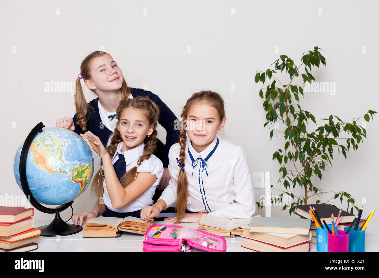 three girls in the classroom studying geography globe of planet Earth ...