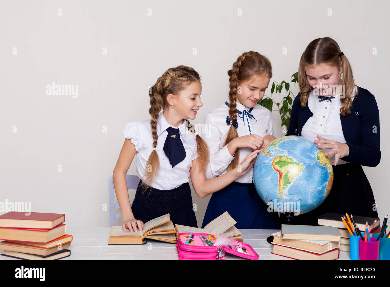 three girls in the classroom studying geography globe of planet Earth ...