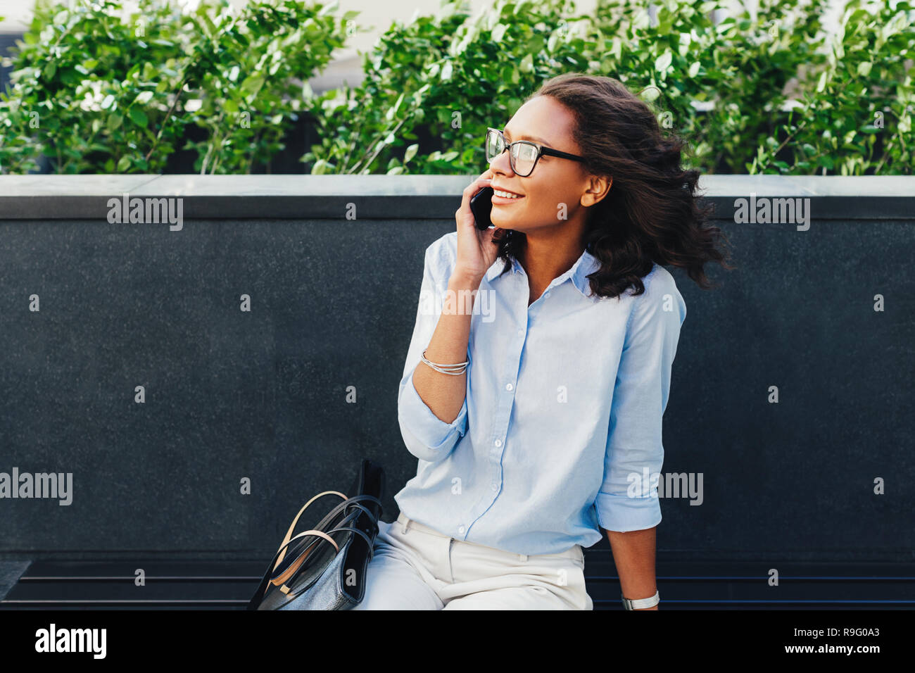 Female entrepreneur sitting outdoors using mobile phone Stock Photo