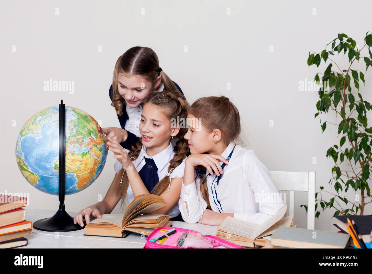 three girls in the classroom studying geography globe of planet Earth ...