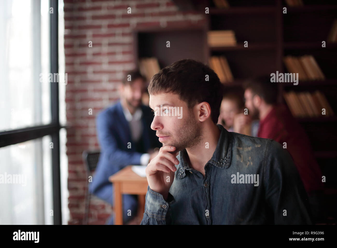 pensive young designer looking out the office window. Stock Photo