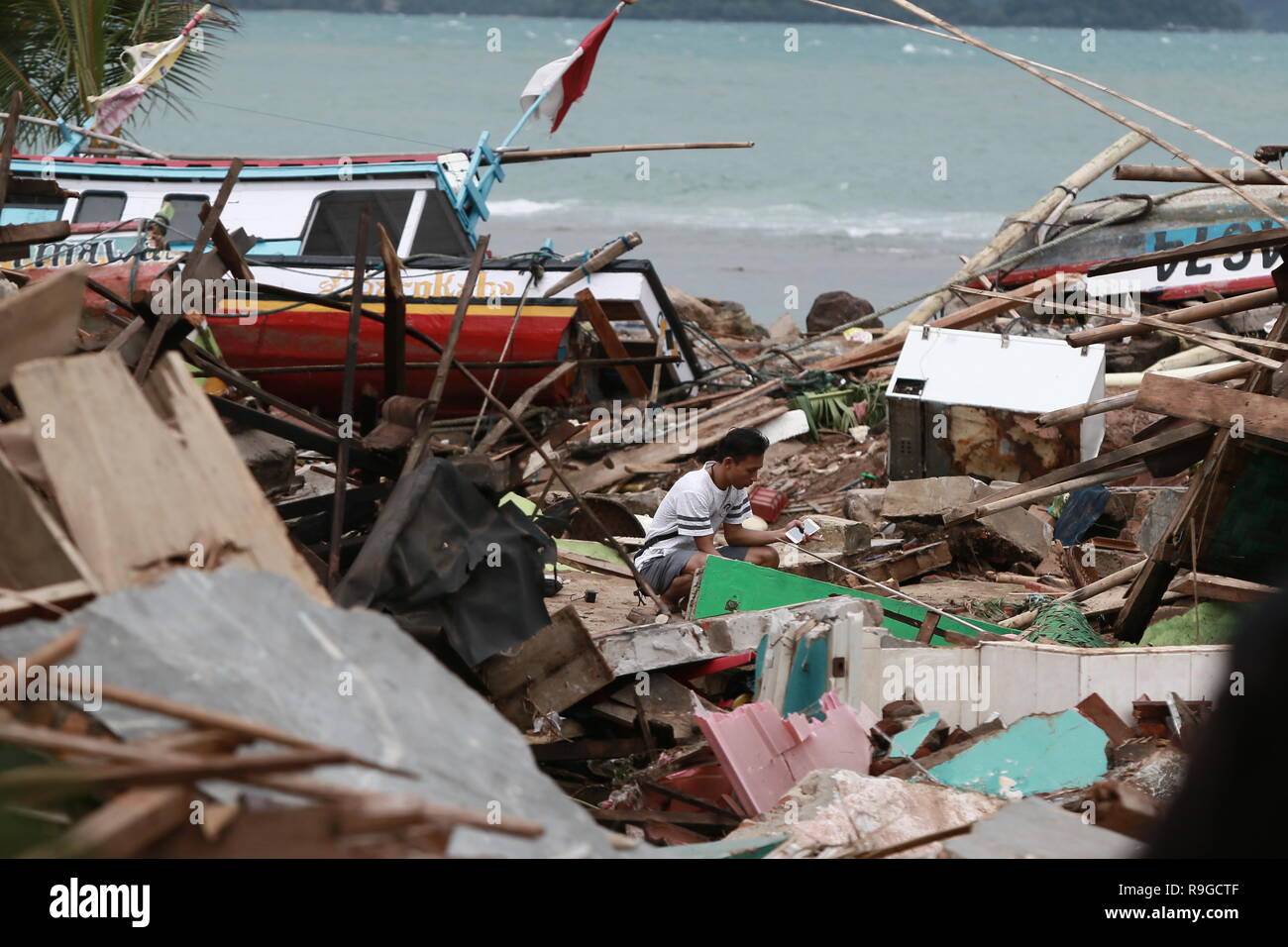 Lampung. 23rd Dec, 2018. A man looks for salvageable items among the debris after a tsunami hit beach at Rajabasa Village in South Lampung, Indonesia, Dec. 23. 2018. The death toll from a volcano-triggered tsunami in Indonesia rose to 222 with at least 843 others injured, the disaster management agency confirmed on Sunday, while the figures are feared to mount as damage verification goes on. Credit: Langit/Xinhua/Alamy Live News Stock Photo