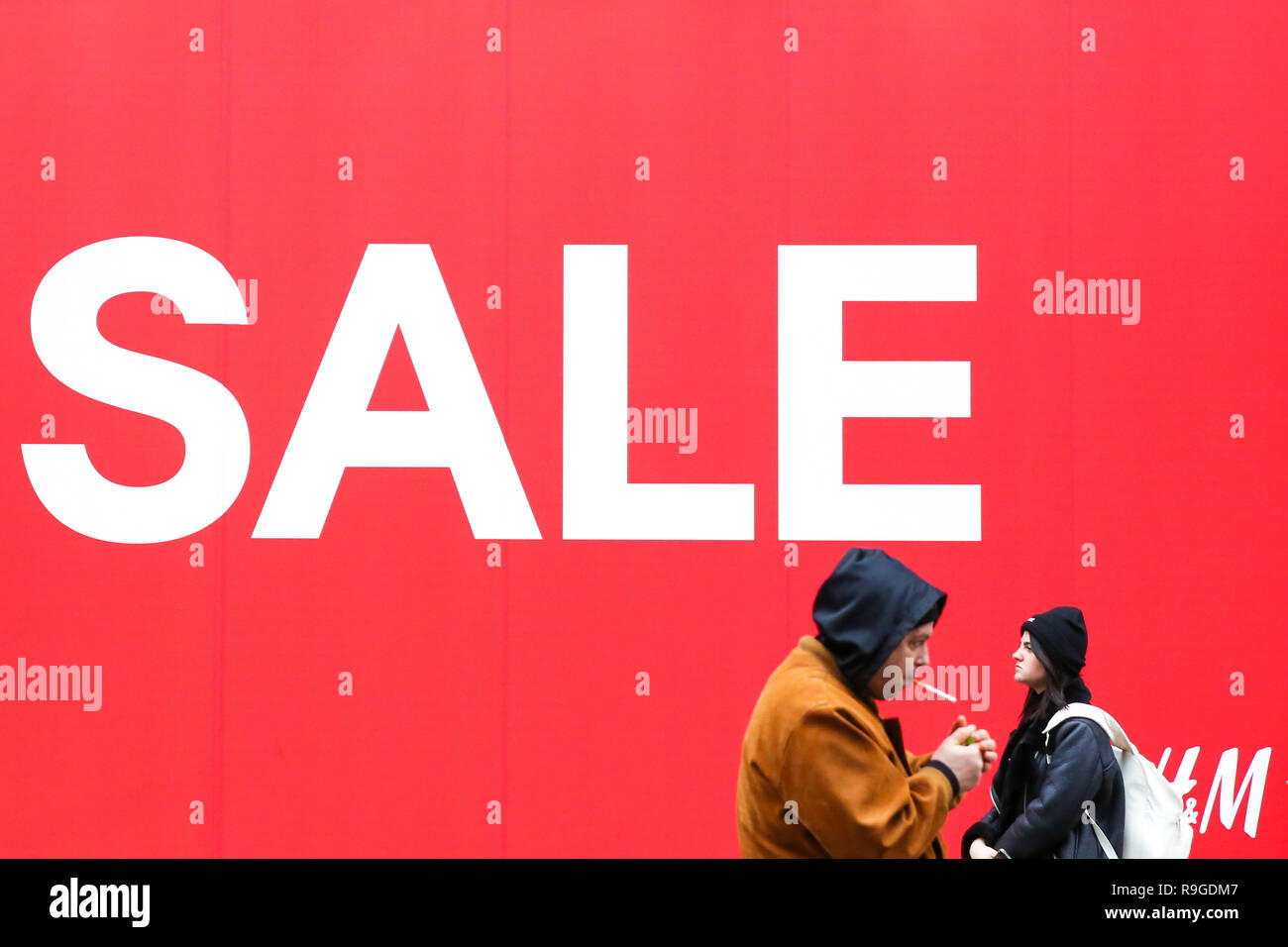 Shoppers are seen walking past H&M window display with a large SALE sign.  Last minute Christmas shoppers take advantage of pre-Christmas bargains at  Oxford Street in London. Fewer shoppers have been reported