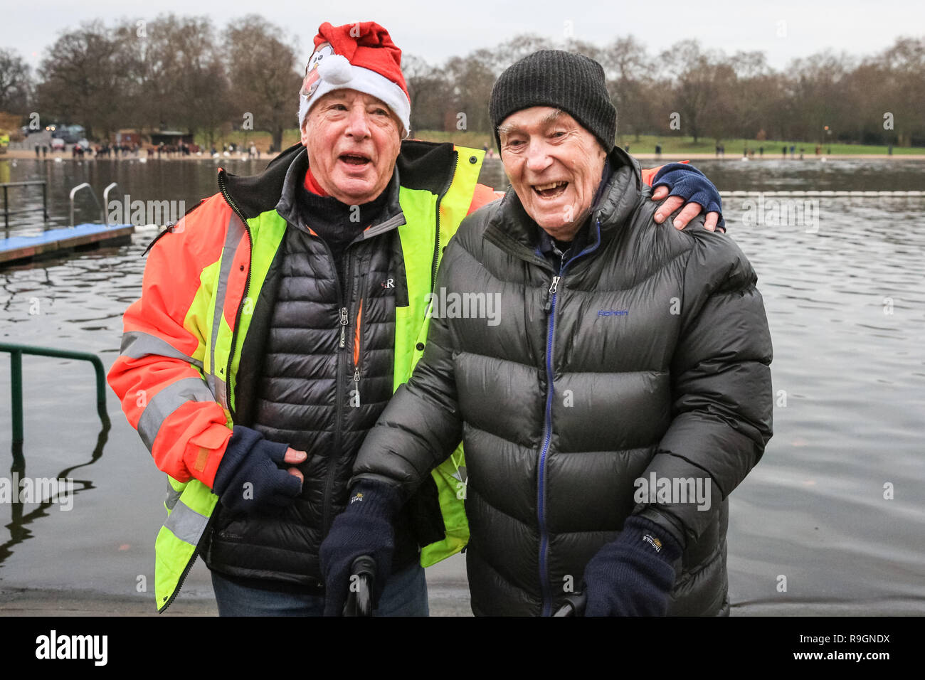 Hyde Park, London, 25th Dec 2018. The Serpentine Club President with the Club's oldest member, Alan Lacy, who is 95 and in good spirits. The 154th annual Christmas morning race for the 'Peter Pan Cup' gets under way at the Serpentine Swimming Club in London's Hyde Park. Swimmers brave the wintry weather and freezing cold open water of the Serpentine for the traditional event. Credit: Imageplotter News and Sports/Alamy Live News Stock Photo