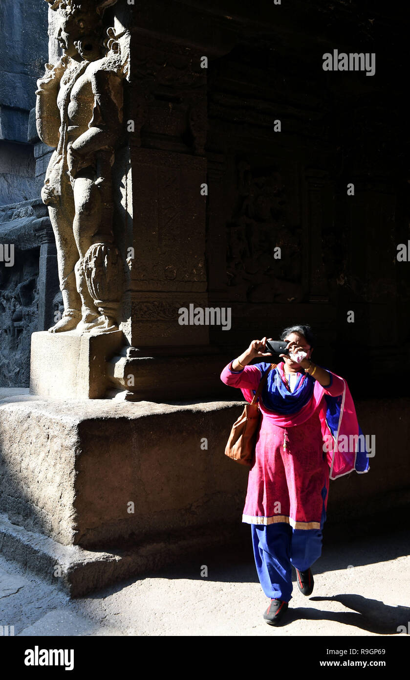 (181225) -- AURANGABAD, Dec. 25, 2018 (Xinhua) -- A tourist takes photos at the Ellora Caves near Aurangabad in Maharashtra, India, on Dec. 23, 2018. The 34 monasteries and temples, extending over more than 2 km, were dug side by side in the wall of a high basalt cliff, not far from Aurangabad, in Maharashtra. Ellora, with its uninterrupted sequence of monuments dating from A.D. 600 to 1000, brings the civilization of ancient India to life. Not only is the Ellora complex a unique artistic creation and a technological exploitation but, with its sanctuaries devoted to Buddhism, Hinduism and Jain Stock Photo