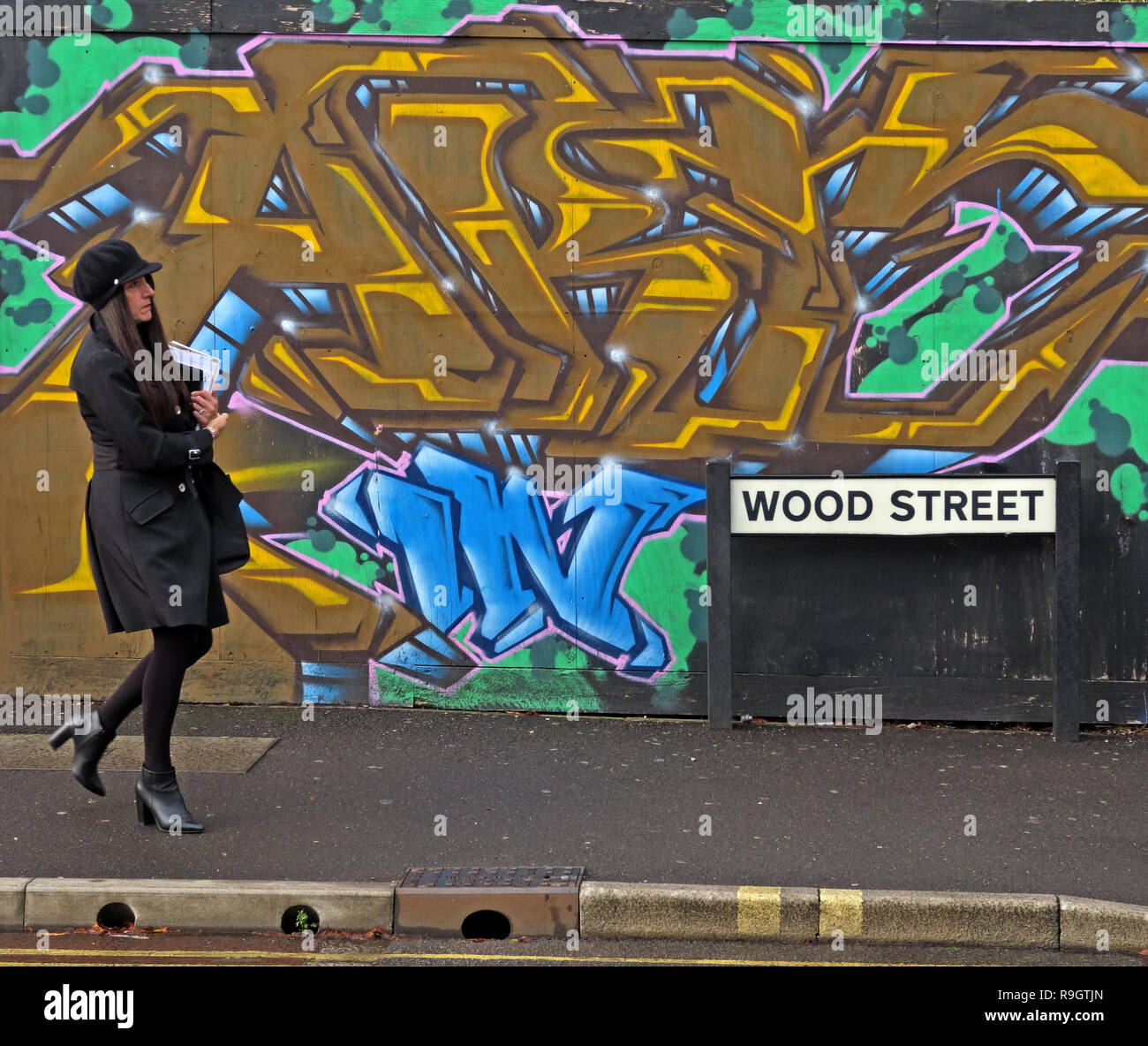 Woman in black walking past colourful graffiti, in Wood street, Taunton, Somerset, South West England, UK, TA1 1UN Stock Photo