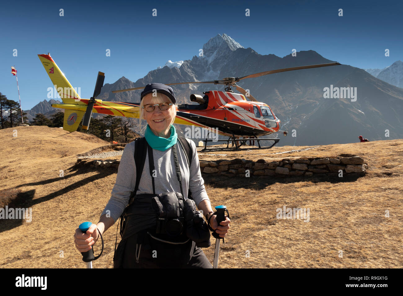 Nepal, Everest Base Camp Trek, Everest View Hotel, trekker resting by helipad beside Shree Airlines AS350 b3e Helicopter Stock Photo