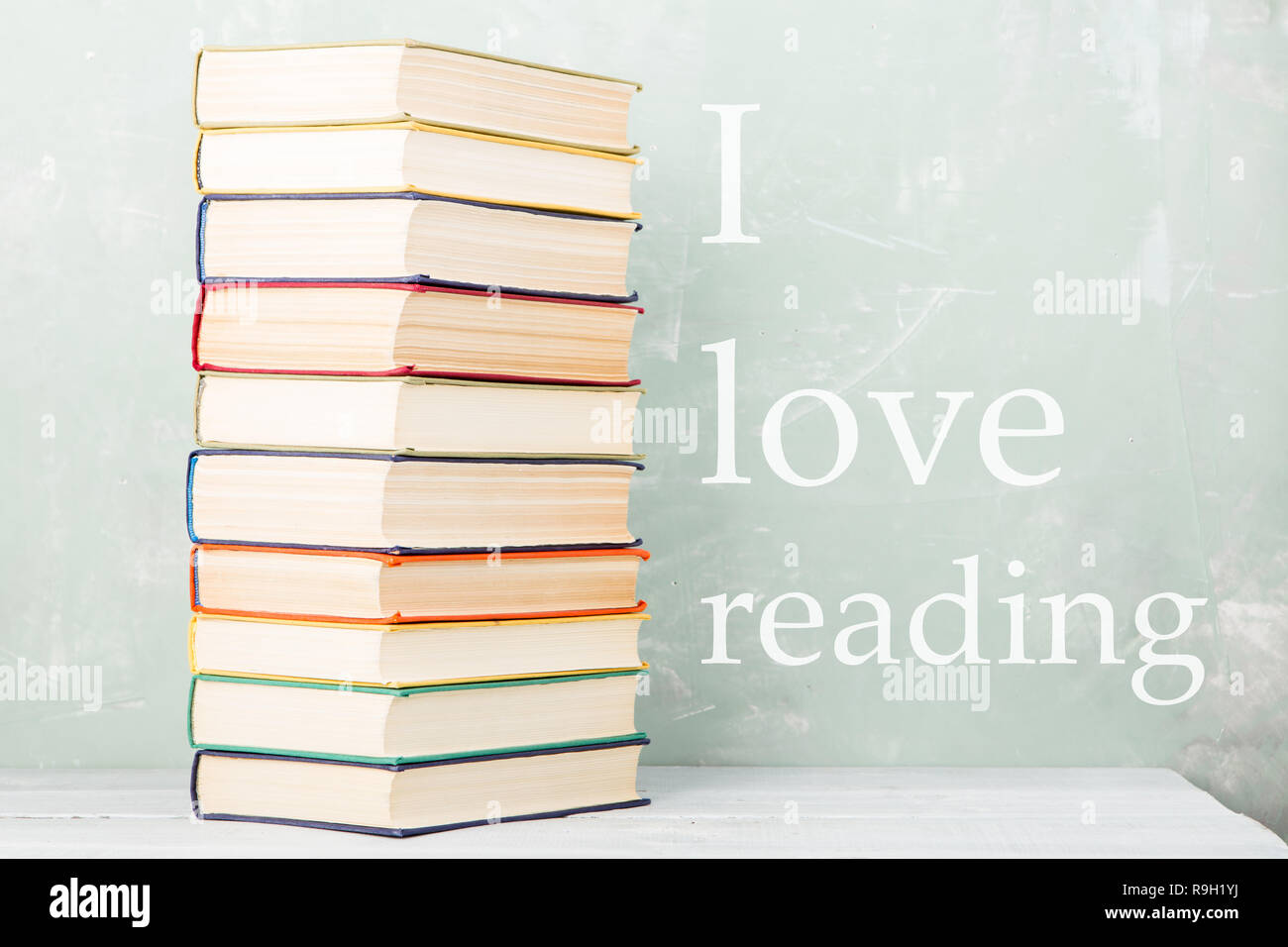 A stack of old colored books on shelf and green background with text 'I love reading' Stock Photo