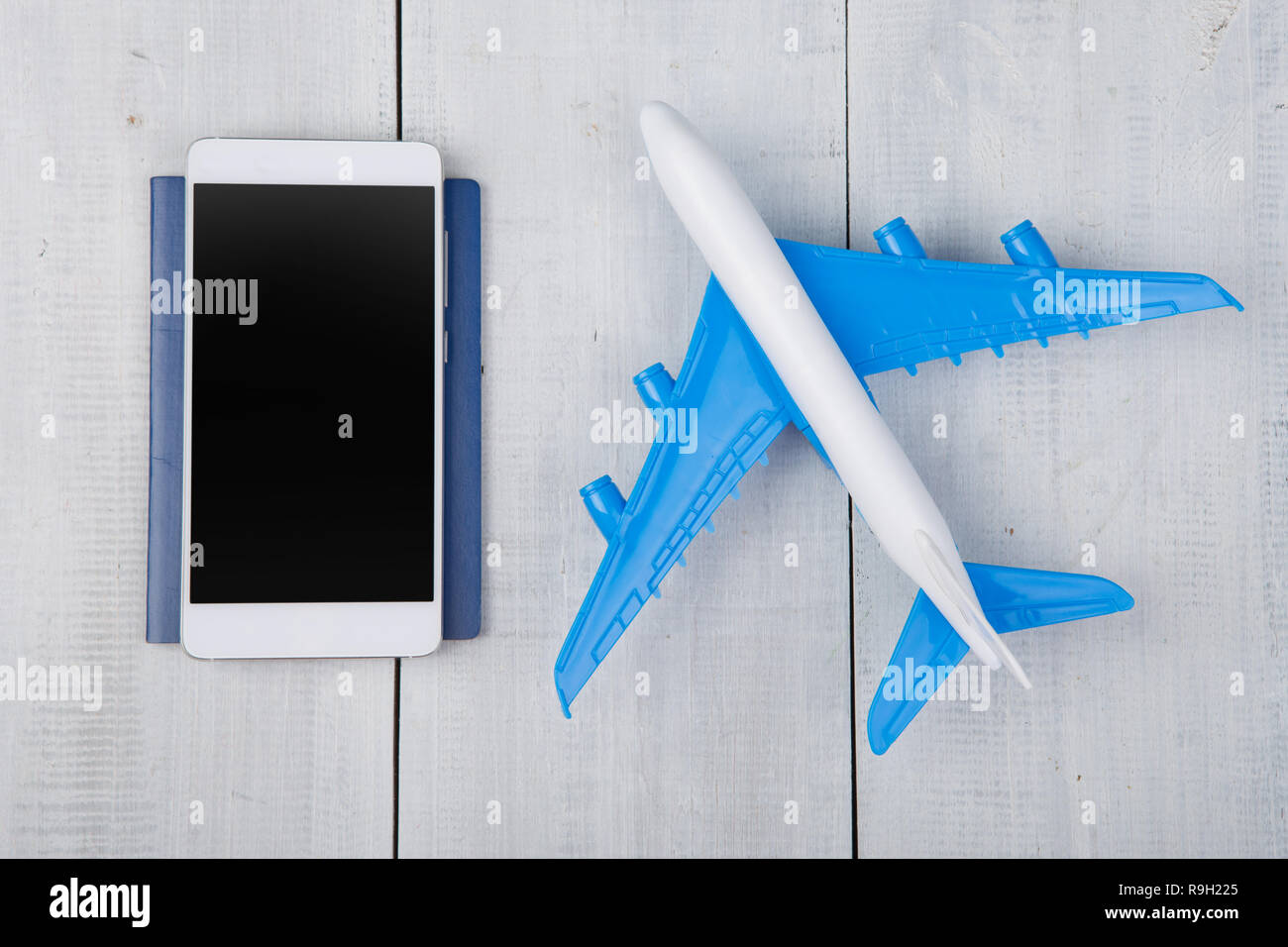 Adventure time - plane, passport and blank smartphone on white wooden table Stock Photo