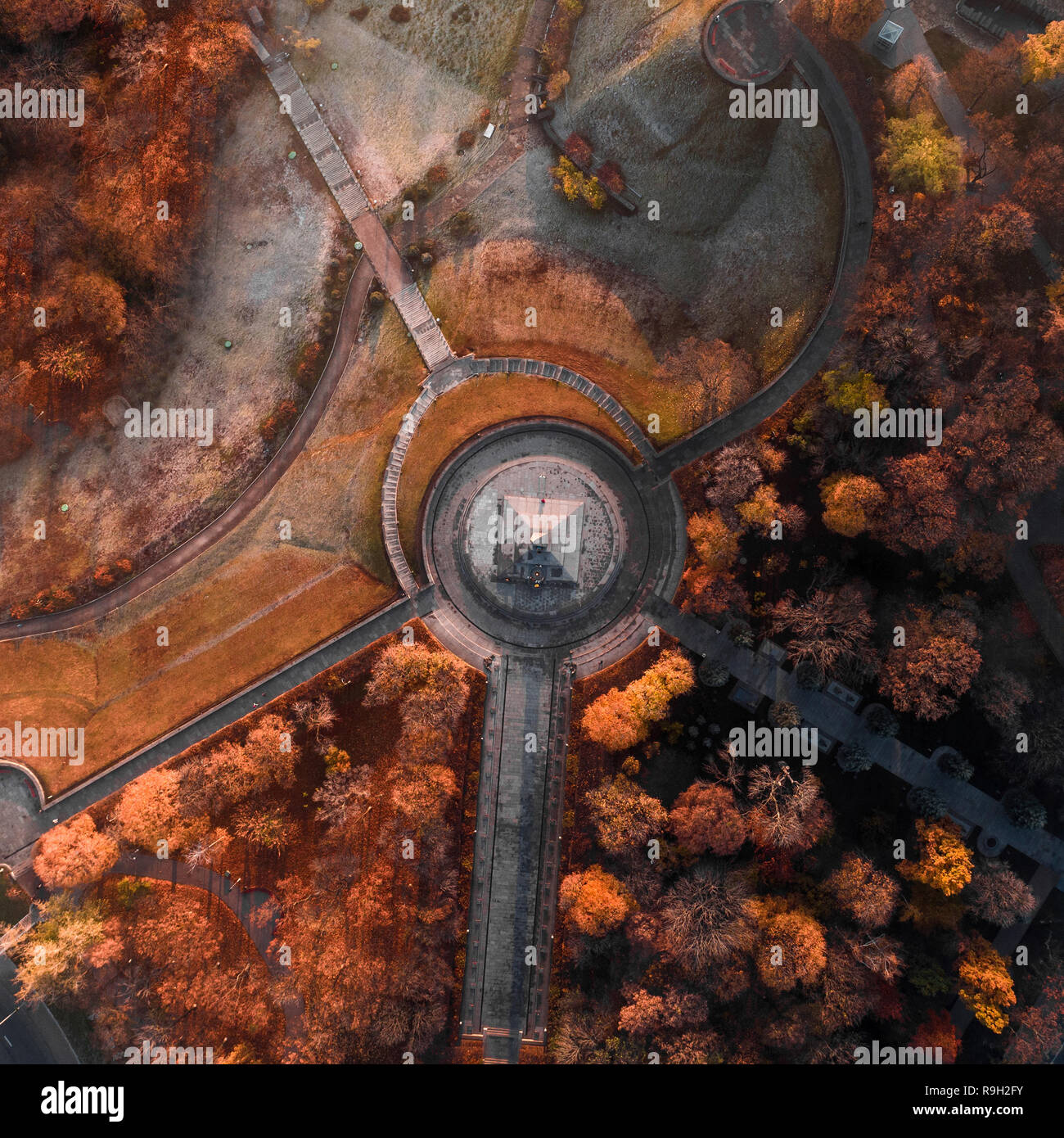Aerial view of a beautiful autumn park with walkways and a monument in ...