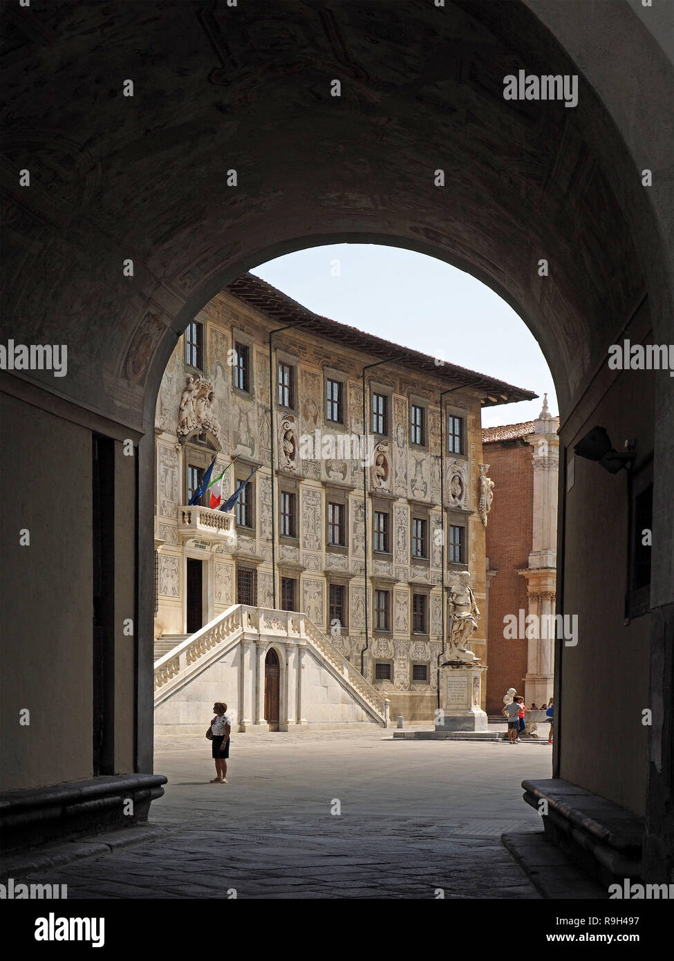 Tourist viewing the Scuole Normale Superiore (SNS or Normale) framed by a vaulted arch into Piazza dei Cavelieri in Pisa,Tuscany,Italy Stock Photo