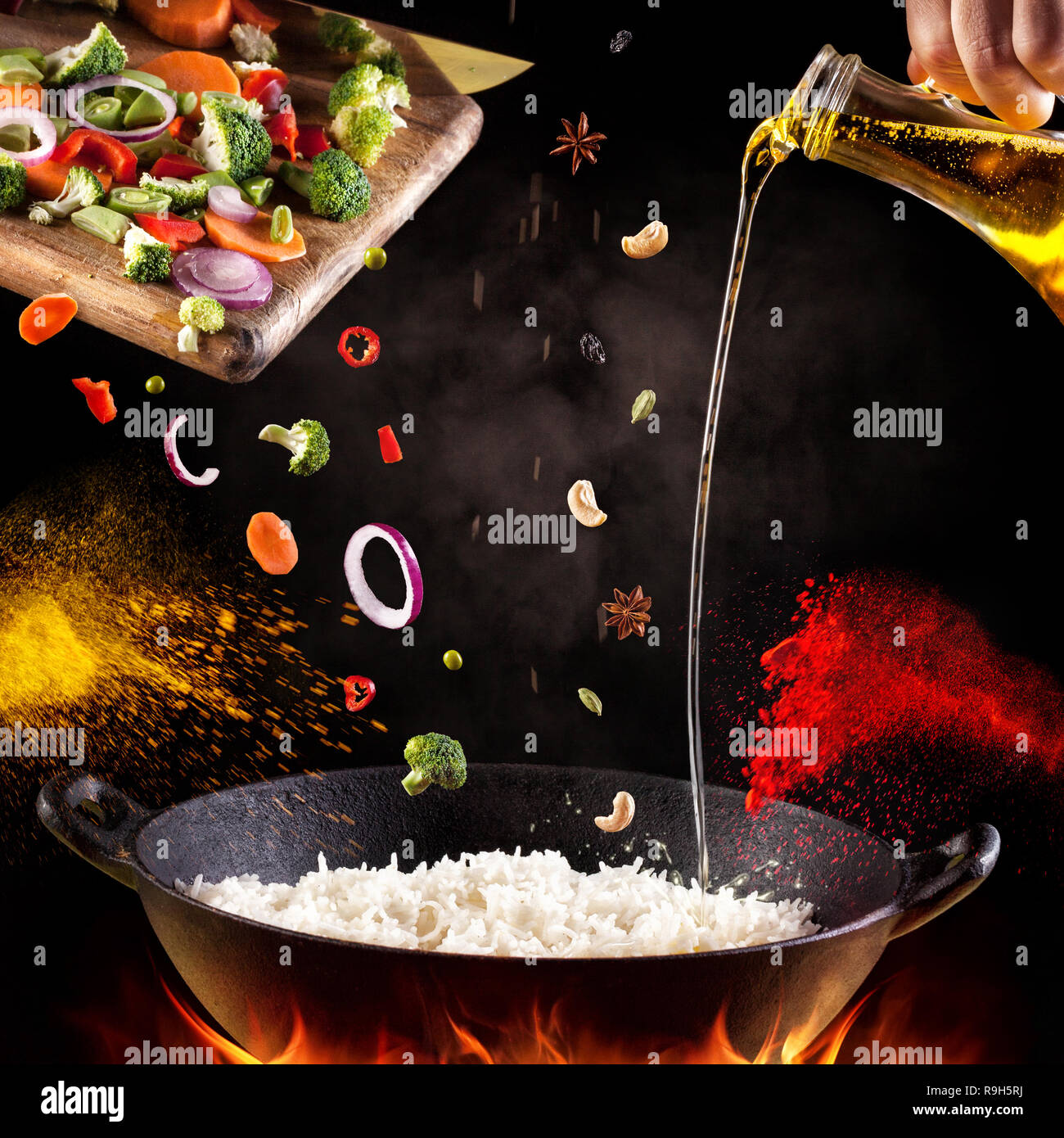 Indian vegetarian biryani with vegetables and spices in cooking process on black background Stock Photo