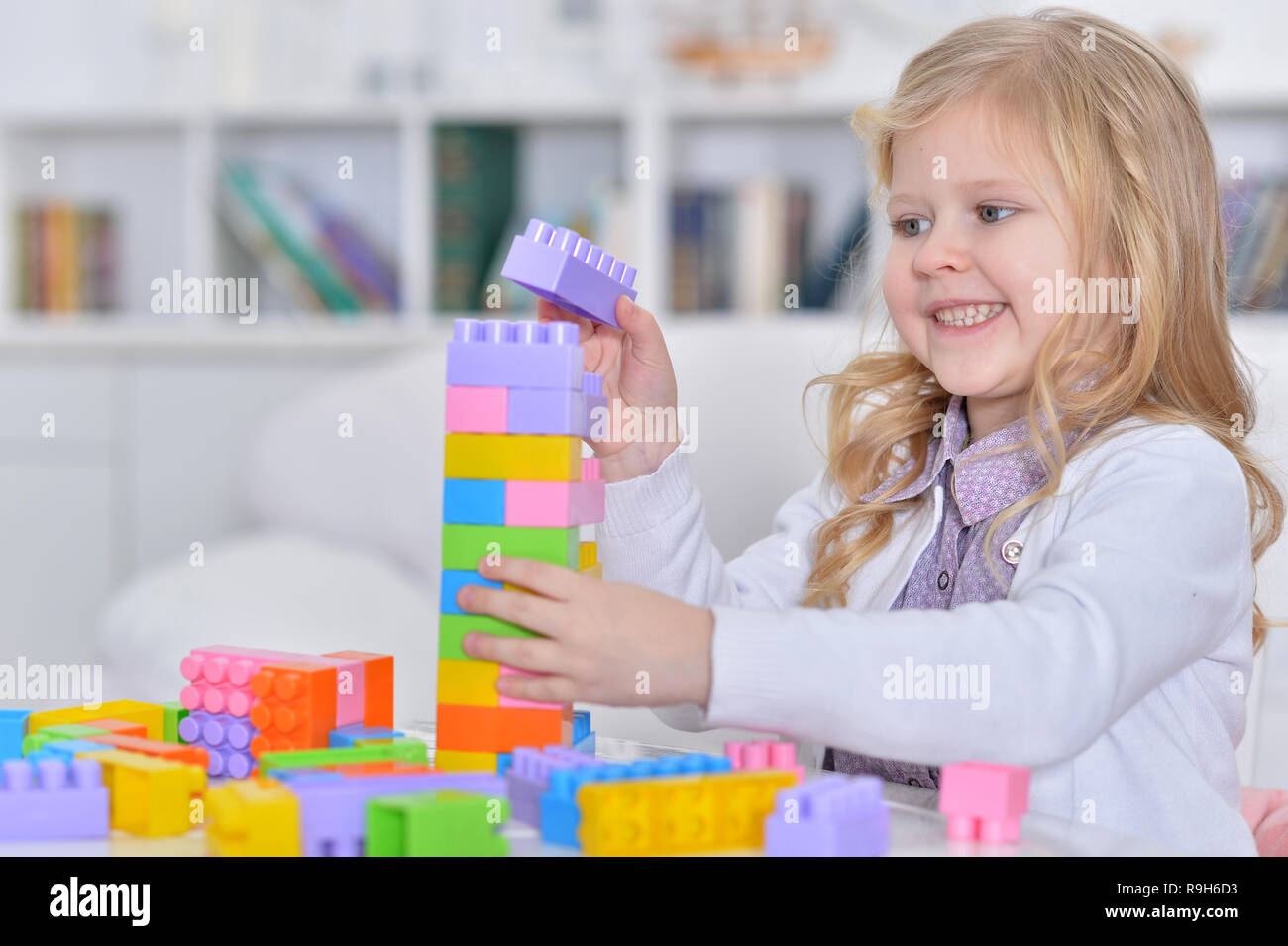 Happy cute little girl playing with colorful plastic blocks Stock Photo ...
