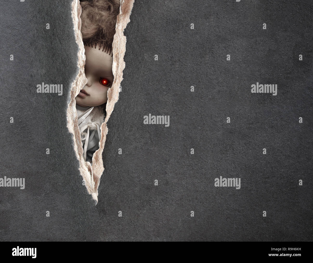 Dark series a look from darkness. Eyes of spooky doll in paper hole