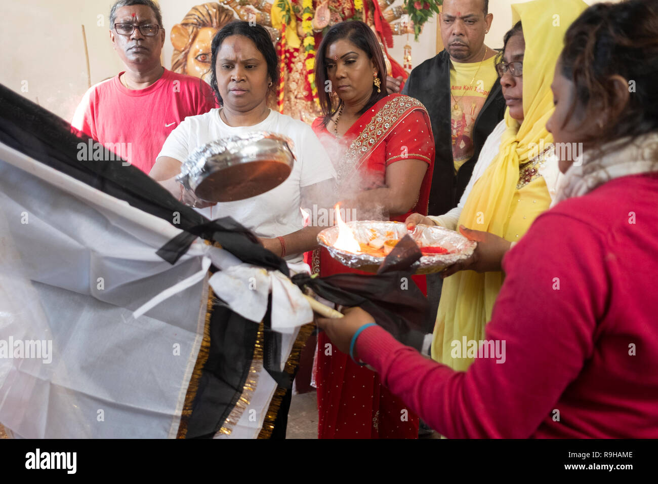 A hindu congregation in performs the Arti ritual of offering light and flames to the deities. In Queens, New York City. Stock Photo